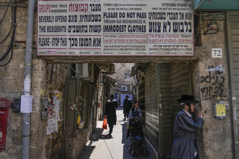 FILE - Ultra-Orthodox Jews walk past a sign calling on women to dress modestly in the ultra-Orthodox neighborhood of Mea Shearim in Jerusalem on June 7, 2023. Israel is a nation perennially swept up in religious fervor and conflict. And yet, strikingly, a large portion of its population is secular, and even its insular ultra-Orthodox community loses a steady stream of members who tire of its strict religious rules.(AP Photo/Ohad Zwigenberg, File)