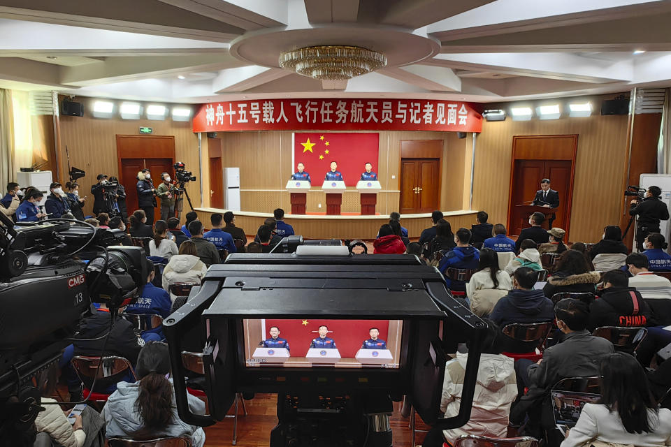 In this photo released by Xinhua News Agency, from left, Chinese astronauts for the upcoming Shenzhou-15 mission Zhang Lu, Fei Junlong and Deng Qingming are seen behind glass during a meeting of the press at the Jiuquan Satellite Launch Center in northwest China on Monday, Nov. 28, 2022. Final preparations were being made Monday to send the new three-person crew to China's space station as it nears completion amid intensifying competition with the United States. (Li Gang/Xinhua via AP)