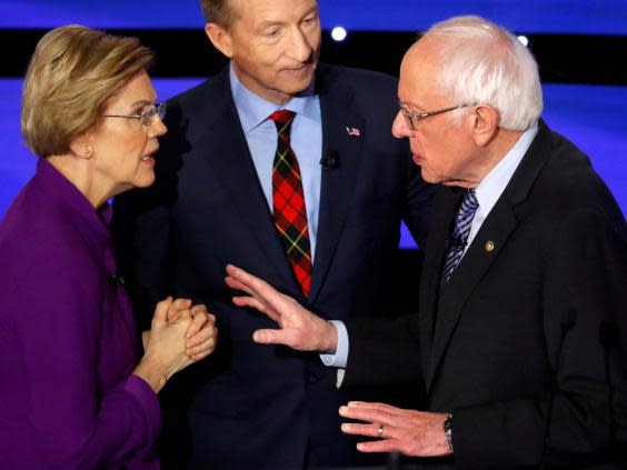 Elizabeth Warren speaks with Bernie Sanders as billionaire activist Tom Steyer listens after the seventh Democratic 2020 presidential debate at Drake University in Des Moines, Iowa on 14 January 2020 (Reuters)