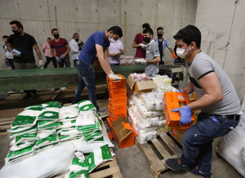 Volunteers wearing protective masks and gloves sort boxes with food for distribution to people in need, in Beirut