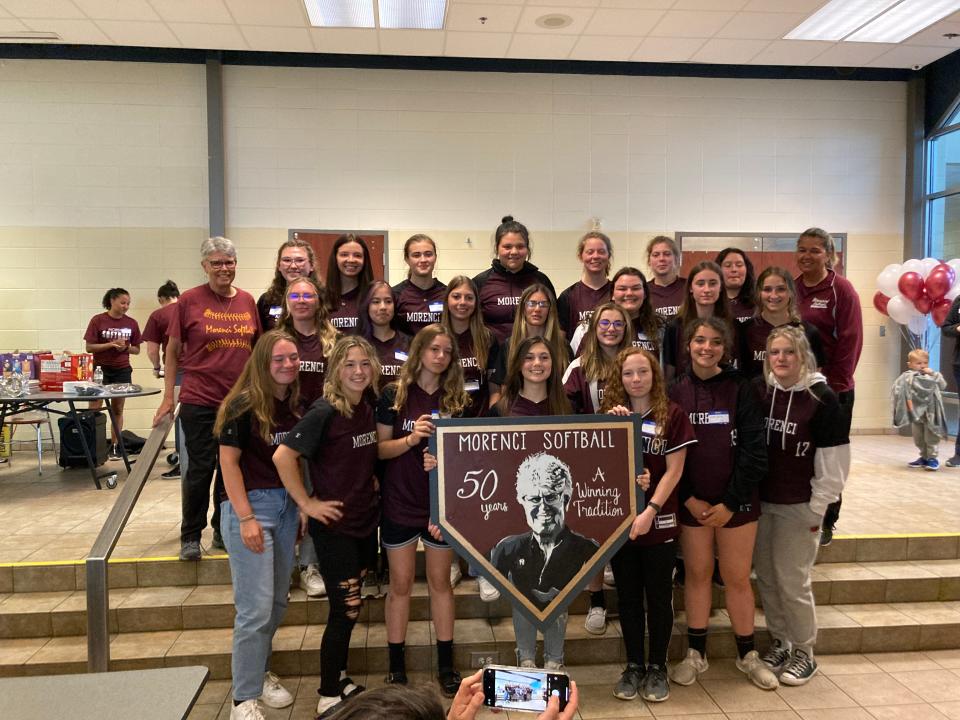 The Morenci softball team present head coach Kay Johnson with a sign to celebrate her 50 years of leading the Bulldogs' softball team.