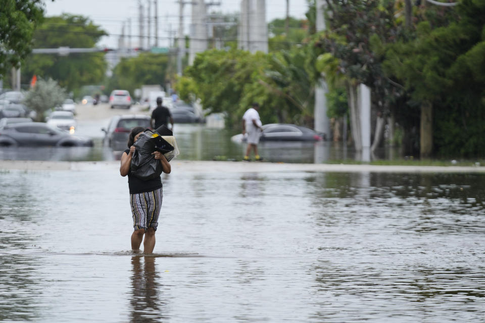 Una mujer camina por una calle inundada en el noreste del condado de Miami-Dade, Florida, el jueves 13 de junio de 2024. (AP Foto/Wilfredo Lee)