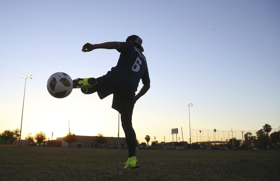 Freddy Sebastian, 20, originally from Guatemala, warms up prior to playing in a Maya Chapin soccer league game Wednesday, April 17, 2019, in Phoenix. As Guatemalans and other Central Americans flood to the U.S.-Mexico border, groups like the Maya Chapin youth soccer group in Phoenix are providing support for young people arriving alone or with families. (AP Photo/Ross D. Franklin)
