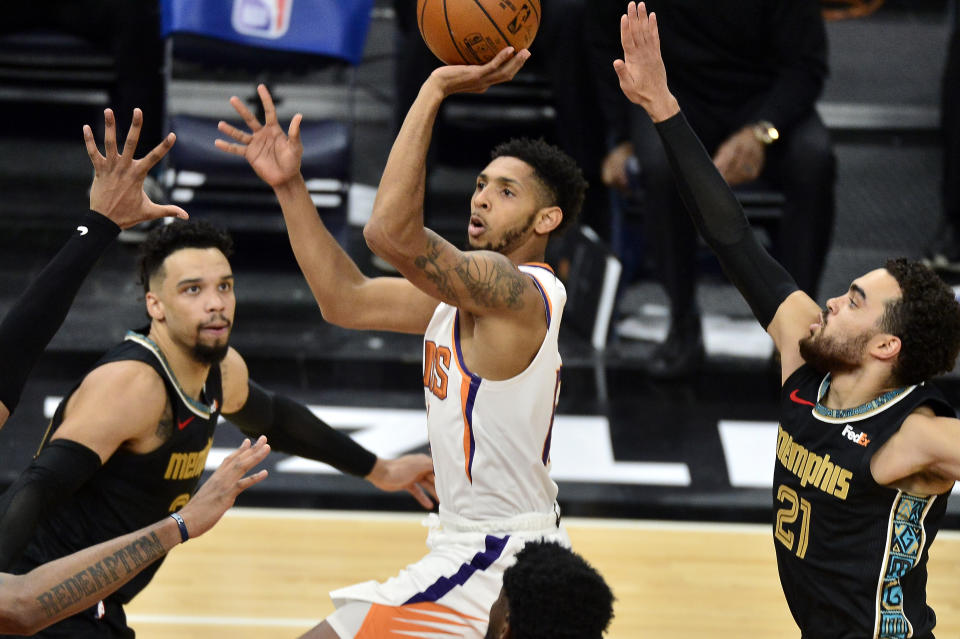 Phoenix Suns guard Cameron Payne (15) shoots between Memphis Grizzlies guards Dillon Brooks (24) and Tyus Jones (21)in the second half of an NBA basketball game Monday, Jan. 18, 2021, in Memphis, Tenn. (AP Photo/Brandon Dill)