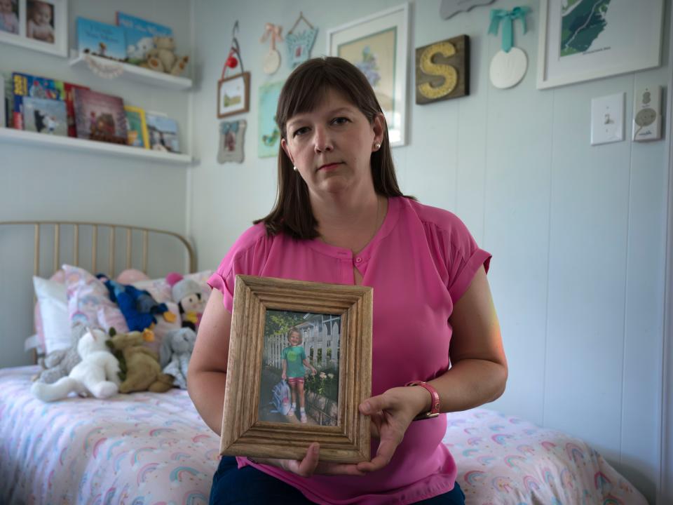 Jessica Hart sitting in Allie's bedroom holding up a photo of Allie.