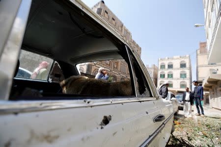 People gather near a car damaged by a mortar shell during fighting between Shi'ite Houthi militants and government forces in Sanaa September 19, 2014. REUTERS/Khaled Abdullah