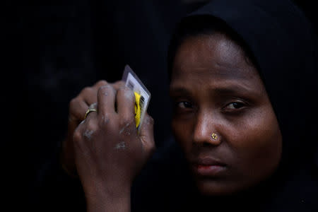 A Rohingya refugee woman holds her identity and work cards after moving mud from the riverbed to help raise the ground level of the camp, in preparation for monsoon season, in Shamlapur refugee camp in Cox's Bazaar, March 25, 2018. REUTERS/Clodagh Kilcoyne