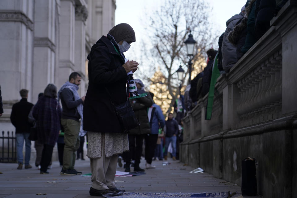 A woman prays on the route as she takes part in a pro-Palestinian demonstration as they wend their way along Whitehall in London, Saturday, Nov. 25, 2023. (AP Photo/Alberto Pezzali)