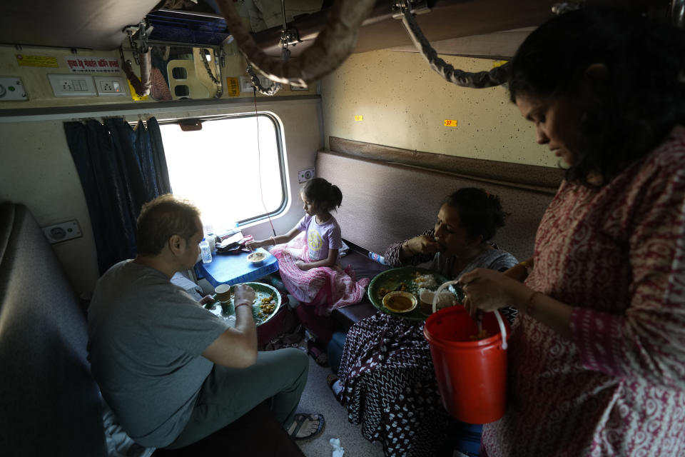 A family on a pilgrimage eats lunch while traveling in an air-conditioned sleeper compartment of the Thirukkural Express, India, Sunday, April 21, 2024. (AP Photo/Manish Swarup)