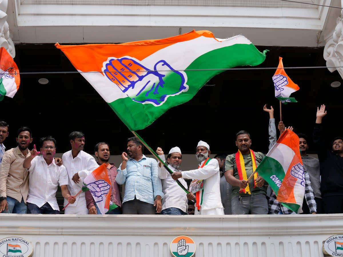 Supporters of opposition Congress party wave flags to celebrate in Karnataka  (AP)