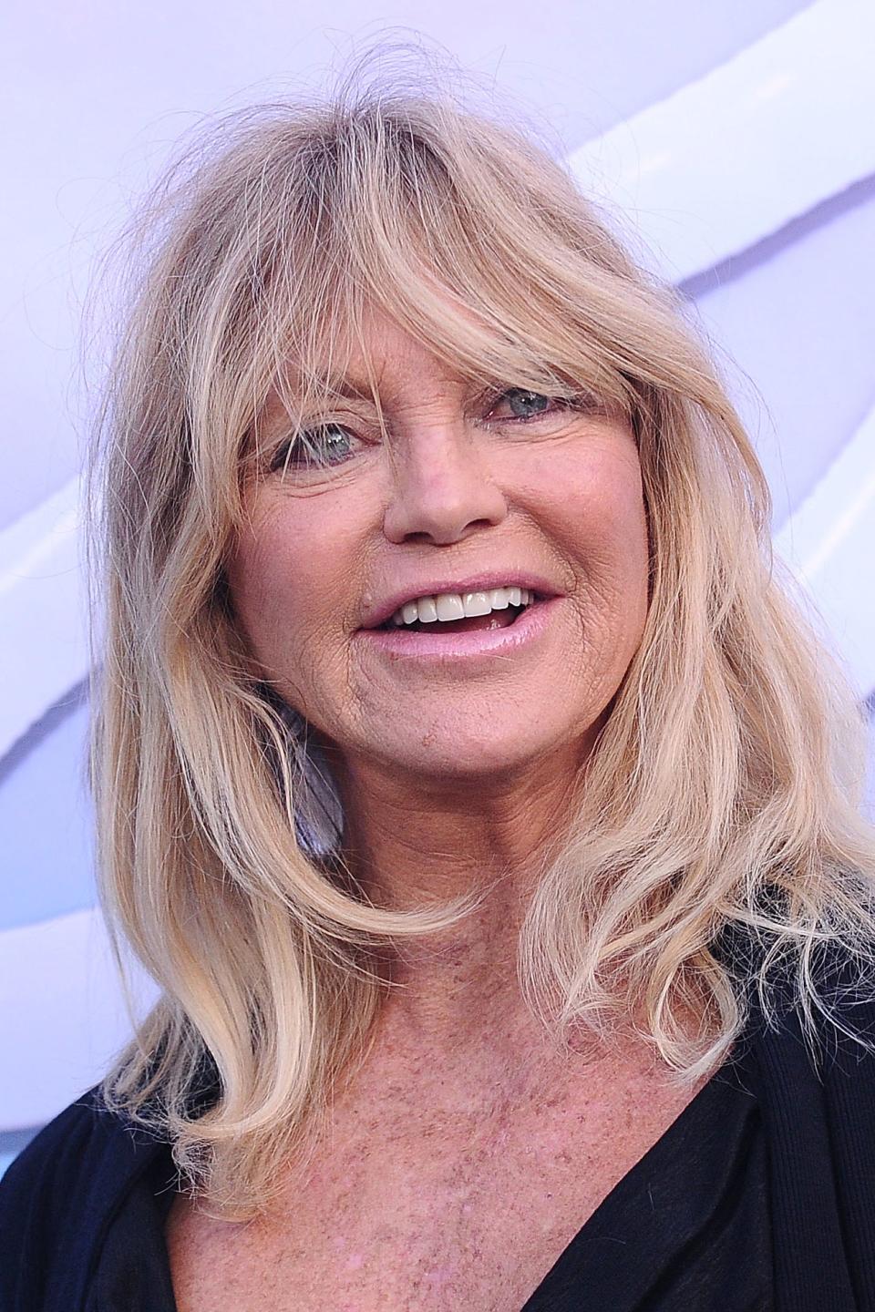 Goldie Hawn smiling at an event, wearing a black outfit
