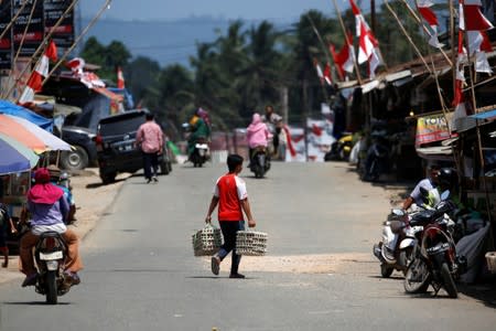 A man carries eggs as he crosses a street at a Sepaku market in North Penajam Paser regency, East Kalimantan province