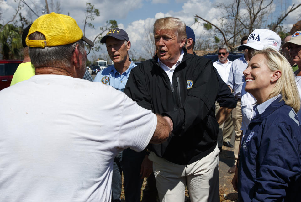 President Donald Trump greets a Lynn Haven, Fla. resident, left, during a tour of a neighborhood affected by Hurricane Michael, Monday, Oct. 15, 2018, in Lynn Haven, Fla. Homeland Security Secretary Kirstjen Nielsen is right and Florida Gov. Rich Scott is left. (AP Photo/Evan Vucci)