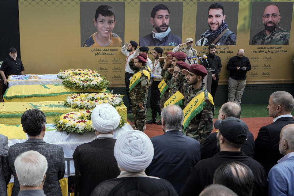 Hezbollah fighters salute as they stand next to the coffins of four victims who were killed Tuesday after their handheld pagers exploded, during their funeral procession in the southern suburb of Beirut, Lebanon, Wednesday, Sept. 18, 2024. (AP Photo/Bilal Hussein)