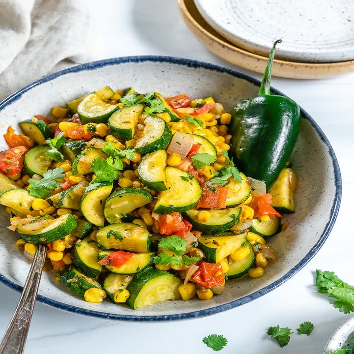 A bowl of cut zucchini, corn, and other colorful ingredients