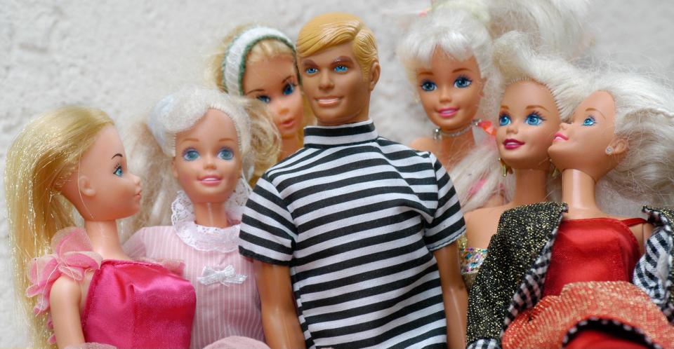 A Ken doll surrounded by six adoring Barbies