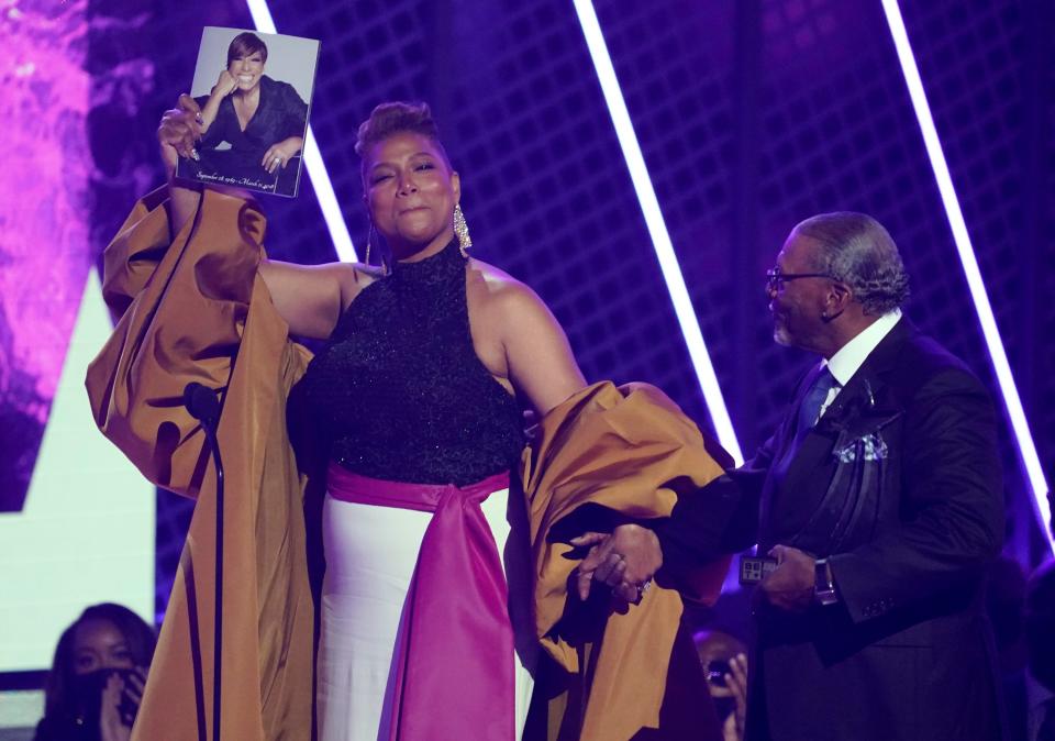 Queen Latifah, winner of the lifetime achievement award, holds a photo of her late mother Rita Owens as she walks with her father Lancelot Owens, Sr.