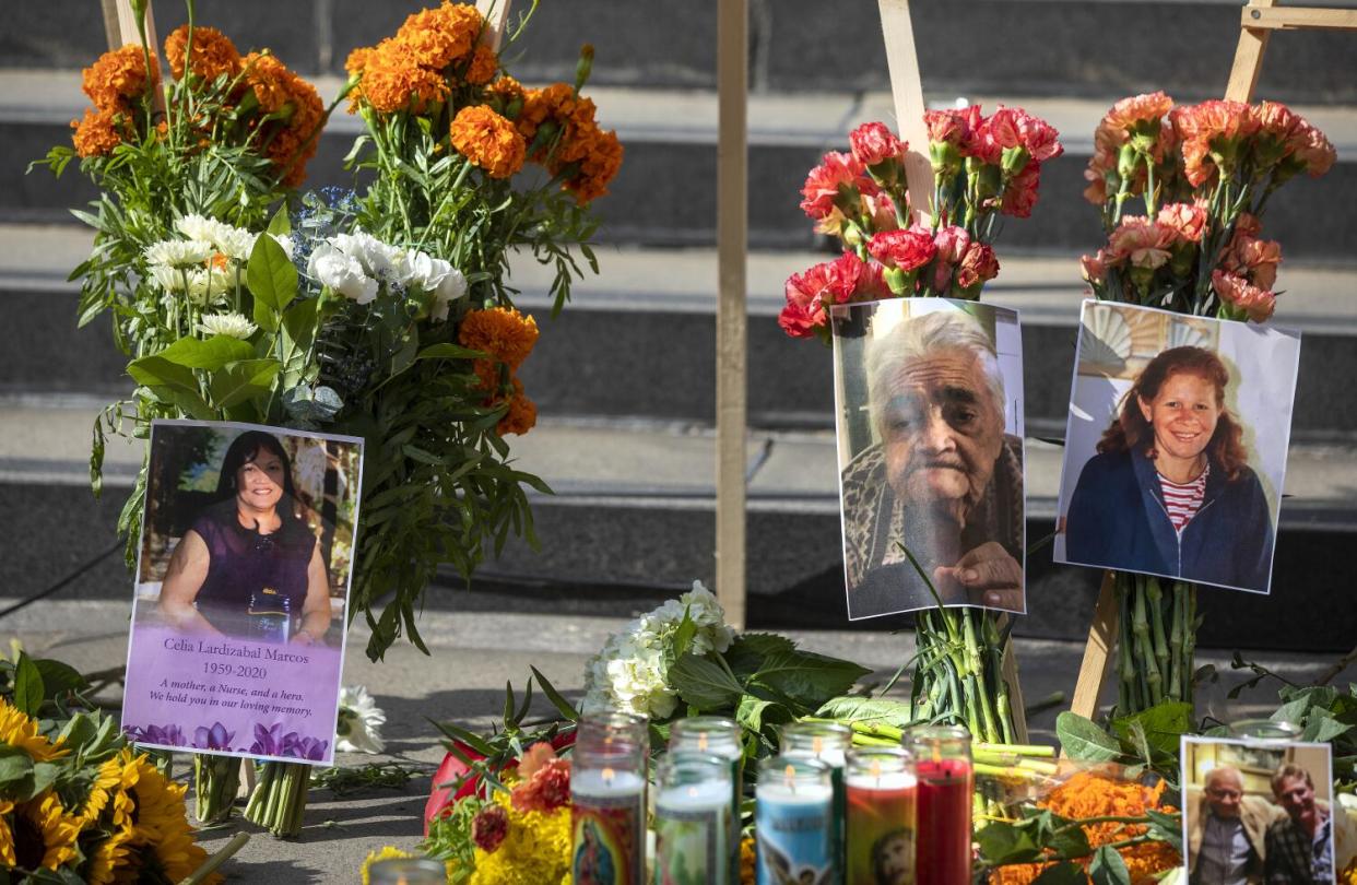 Photos of people who died in the pandemic, including Celia Marcos, left, are part of a memorial in downtown Los Angeles