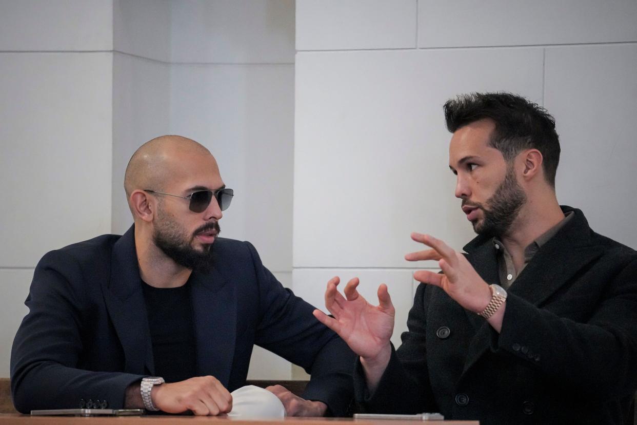 Andrew Tate, right, and his brother Tristan talk inside the Court of Appeal building in Bucharest, Romania, Friday, Dec. 22, 2023. Divisive influencer Andrew Tate and his brother Tristan appeared Friday at the Court of Appeal in Bucharest to ask if he could temporarily leave the country to visit his mother. The hearing comes a day after Tate's spokesperson said their mother suffered a heart attack. (AP Photo/Vadim Ghirda)