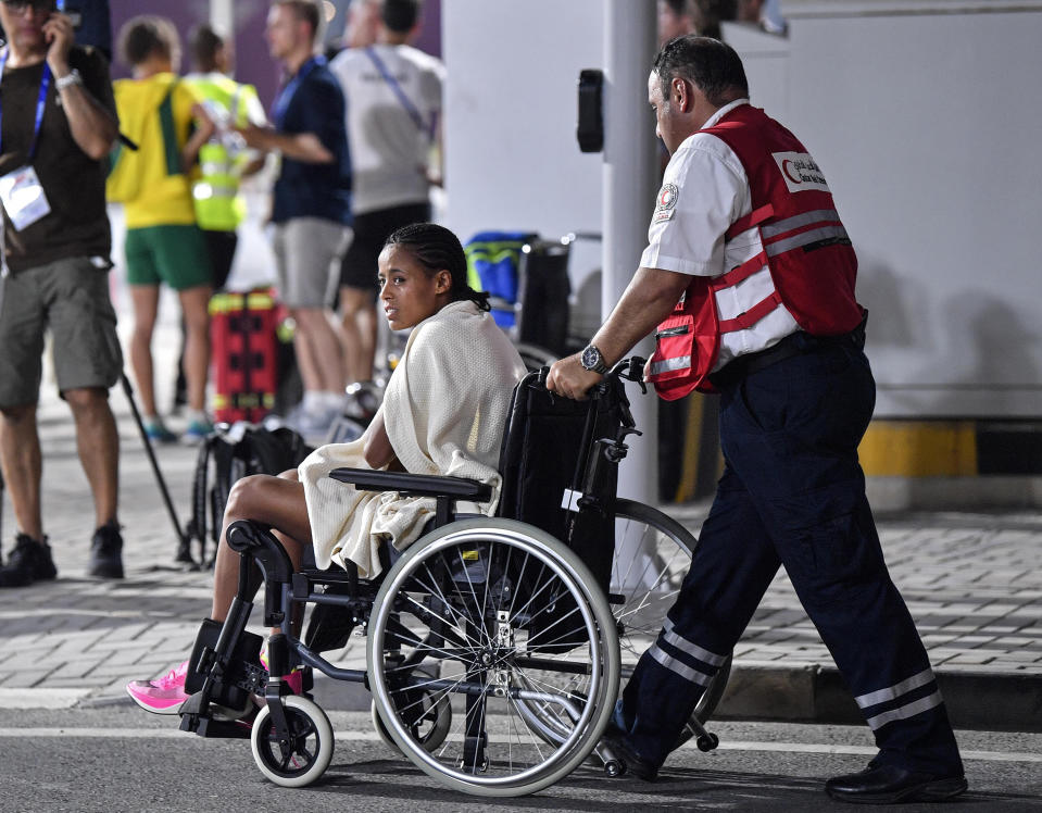 An unidentified competitor is transported by wheelchair after abandoning the women's marathon at the World Athletics Championships in Doha, Qatar, Saturday, Sept. 28, 2019. (AP Photo/Martin Meissner)