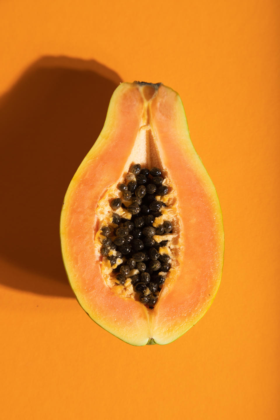 Ripe cut papaya on orange pastel background