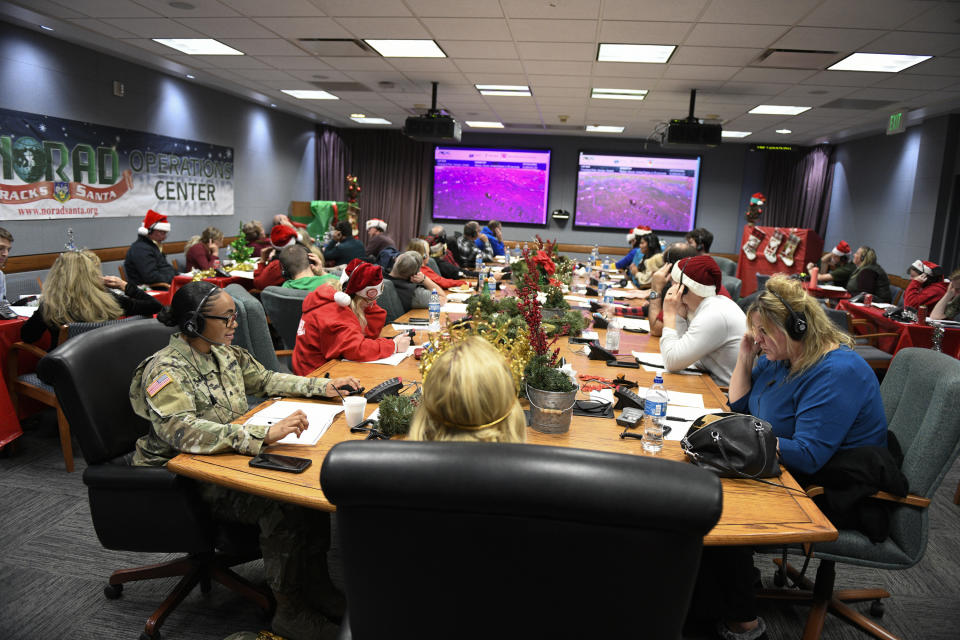 This image provided by the Department of Defense shows volunteers answering phones and emails from children around the globe during the annual NORAD Tracks Santa event on Peterson Air Force Base in Colorado Springs, Colo., Dec. 24, 2022. (Chuck Marsh/Department of Defense via AP)