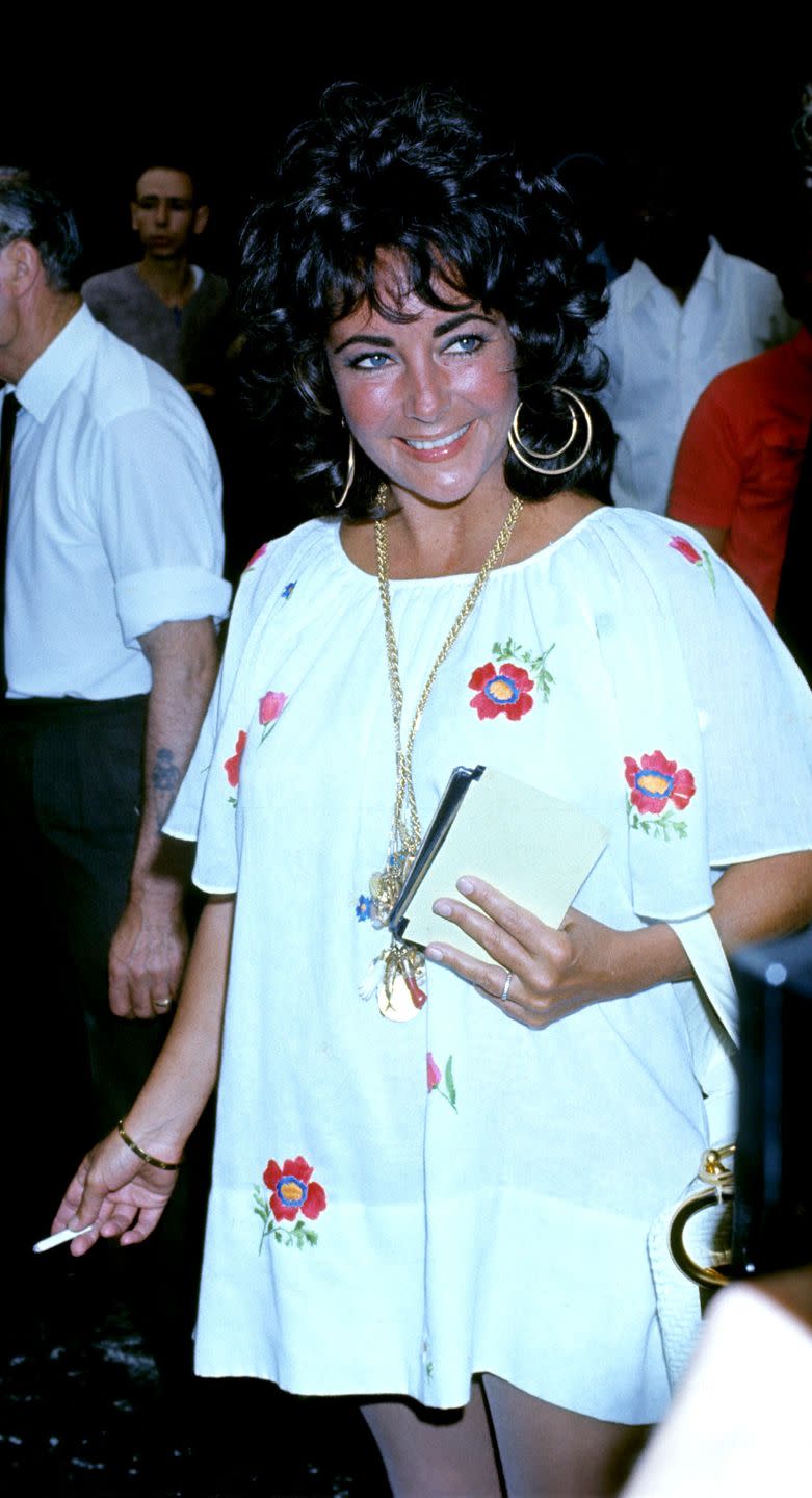 <p>Elizabeth is dialed into the '70s fashion cues as she leaves the airport in London, wearing a floral peasant dress and large gold hoops. </p>