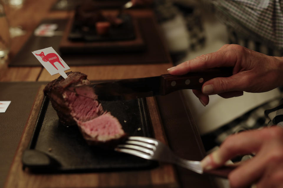 In this March 20, 2017 photo a tourist makes eats meat during an activity called "The Argentine Experience" in Buenos Aires, Argentina. Tourists participating in "The Argentine Experience" have the chance to learn about the local cuisine, wine and traditions during a dinner in Buenos Aires. (AP Photo/Natacha Pisarenko)