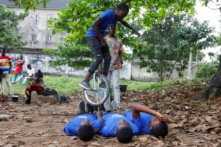 Members of the GKB academy, a unicycle club, perform stunts during a training session in an open field in Lagos
