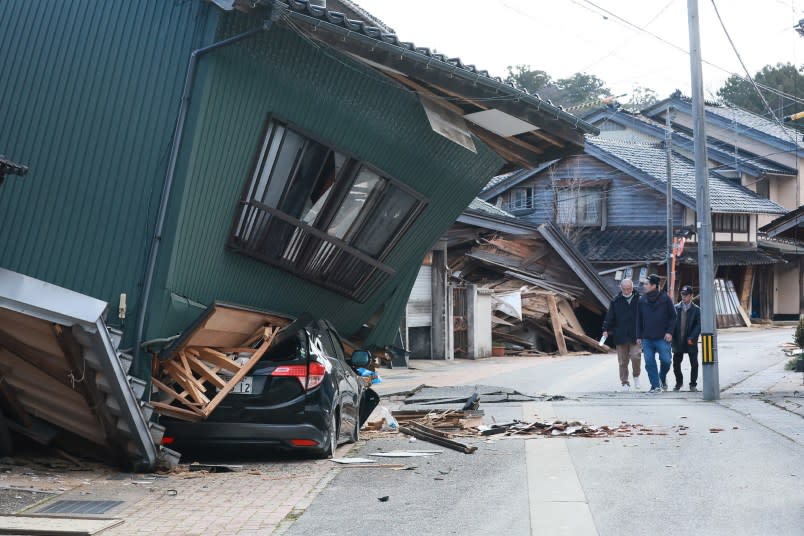 TOPSHOT – People walk past a badly damaged house in the city of Nanao, Ishikawa Prefecture, on January 2, 2024, a day after a major 7.5 magnitude earthquake struck the Noto region in Ishikawa prefecture. Japanese rescuers battled against the clock and powerful aftershocks on January 2 to find survivors of a major earthquake that struck on New Year’s Day, killing at least 48 people and causing widespread destruction. (Photo by JIJI PRESS / AFP) / Japan OUT (Photo by STR/JIJI PRESS/AFP via Getty Images)