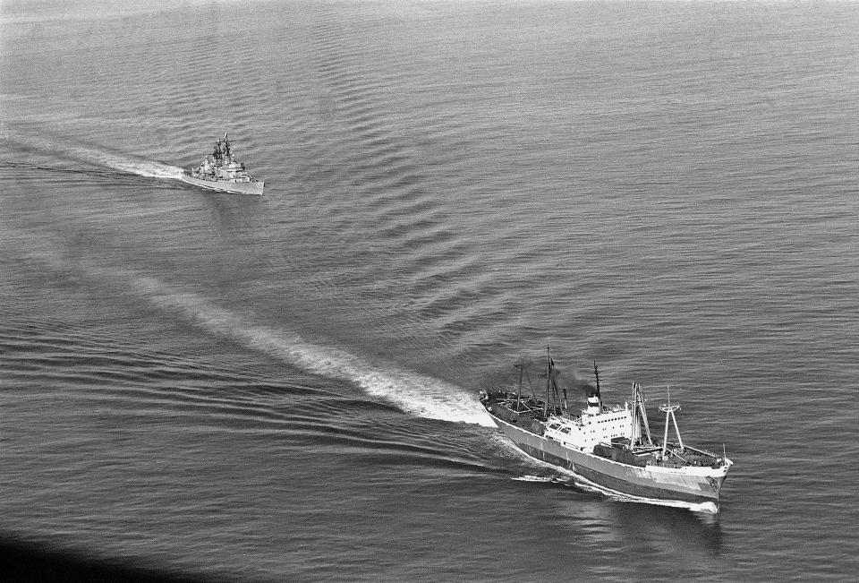 FILE - U.S. Navy guided missile ship Dahlgren trails the Soviet Leninsky Komsomol, Nov. 10, 1962, as the Russian vessel headed from Casilda, Cuba, through the windward passage between Haiti and Cuba. The freighter, loaded with military equipment and missile-like objects covered with canvas, was later intercepted by the destroyer leader Norfolk. After the missiles were detected by reconnaissance flights over Cuba, the US ordered a naval blockade of the island. Tensions soared, but the Soviets agreed to dismantle the missiles and for the US to remove its missiles from Turkey. The positive offshoot was establishment of a US-USSR hotline to facilitate crisis communications. (AP Photo/Henry Burroughs, File)