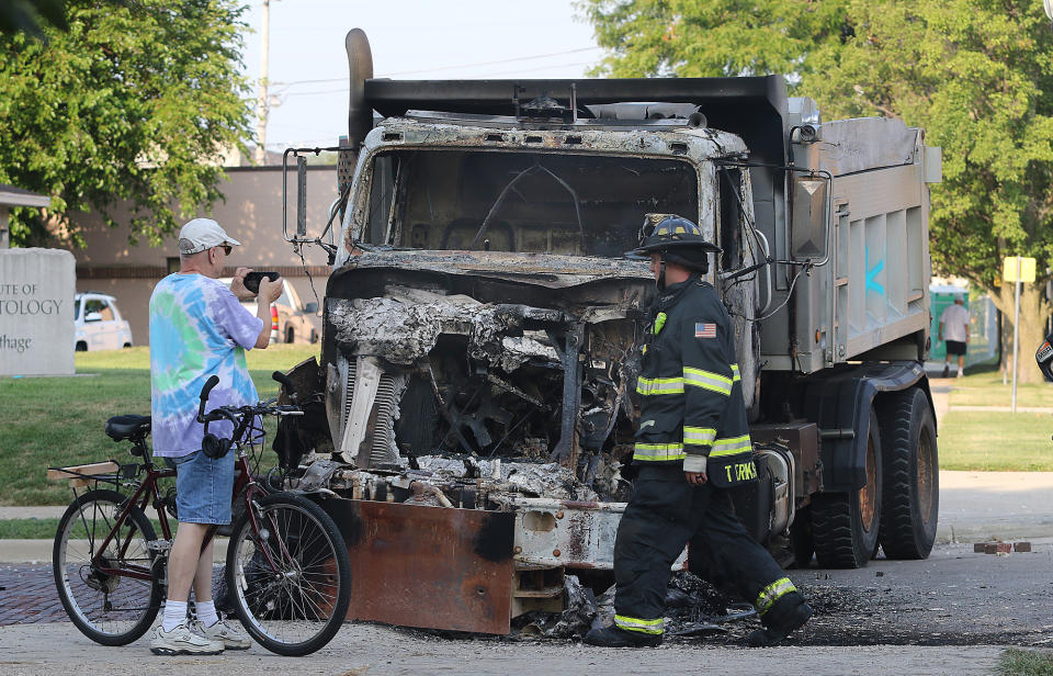 A bystander takes a photo of a burned-out Kenosha service truck Monday outside the courthouse. (Scott Anderson)