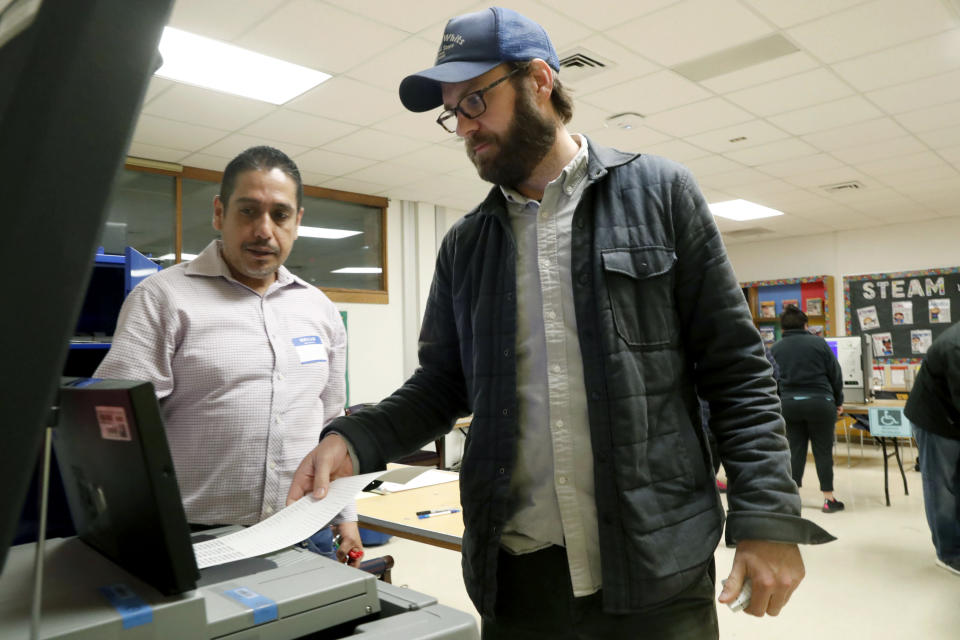 Dallas County election worker Maxx Nuñez helps Democrat Jamie Wilson cast his ballot in the Super Tuesday primary at John H. Reagan Elementary School in the Oak Cliff section of Dallas, Tuesday, March 3, 2020. (AP Photo/LM Otero)