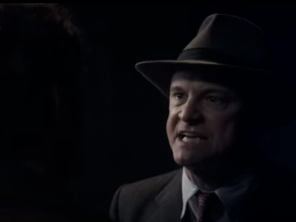 Colin Firth in the shadows wearing a fedora and yelling at Jude Law in "Genius."