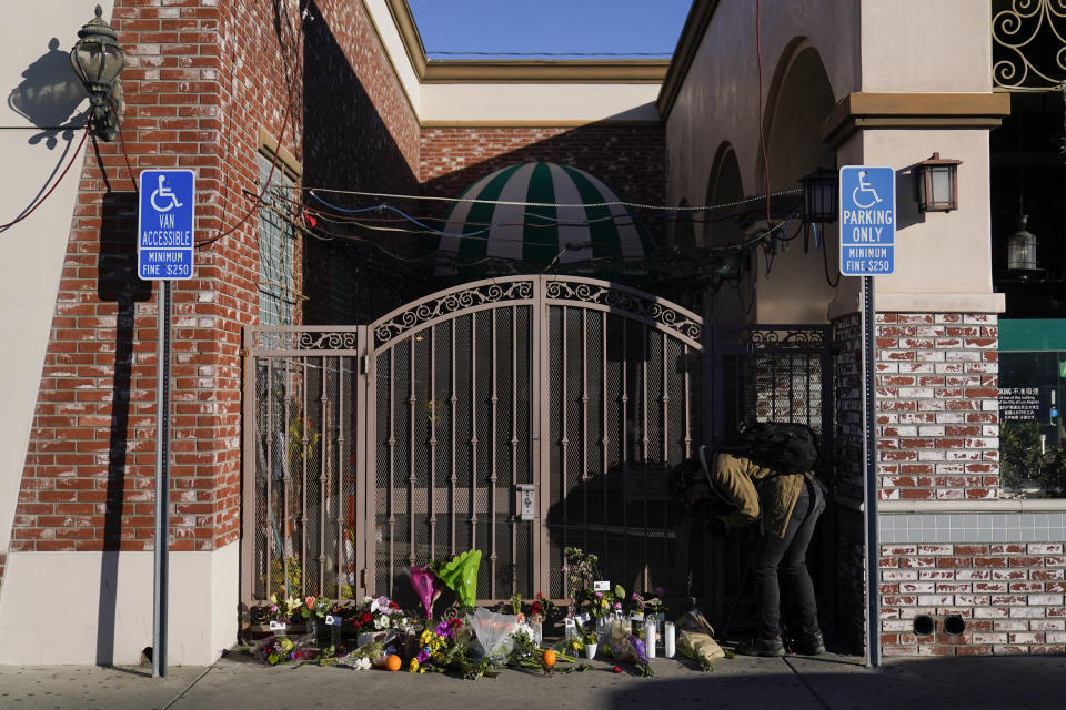 A videographer records flowers and candles placed outside Star Dance Studio in Monterey Park, Calif., Monday, Jan. 23, 2023. Authorities searched for a motive for the gunman who killed multiple people at the ballroom dance club during Lunar New Year celebrations, slayings that sent a wave of fear through Asian American communities and cast a shadow over festivities nationwide. (AP Photo/Jae C. Hong)