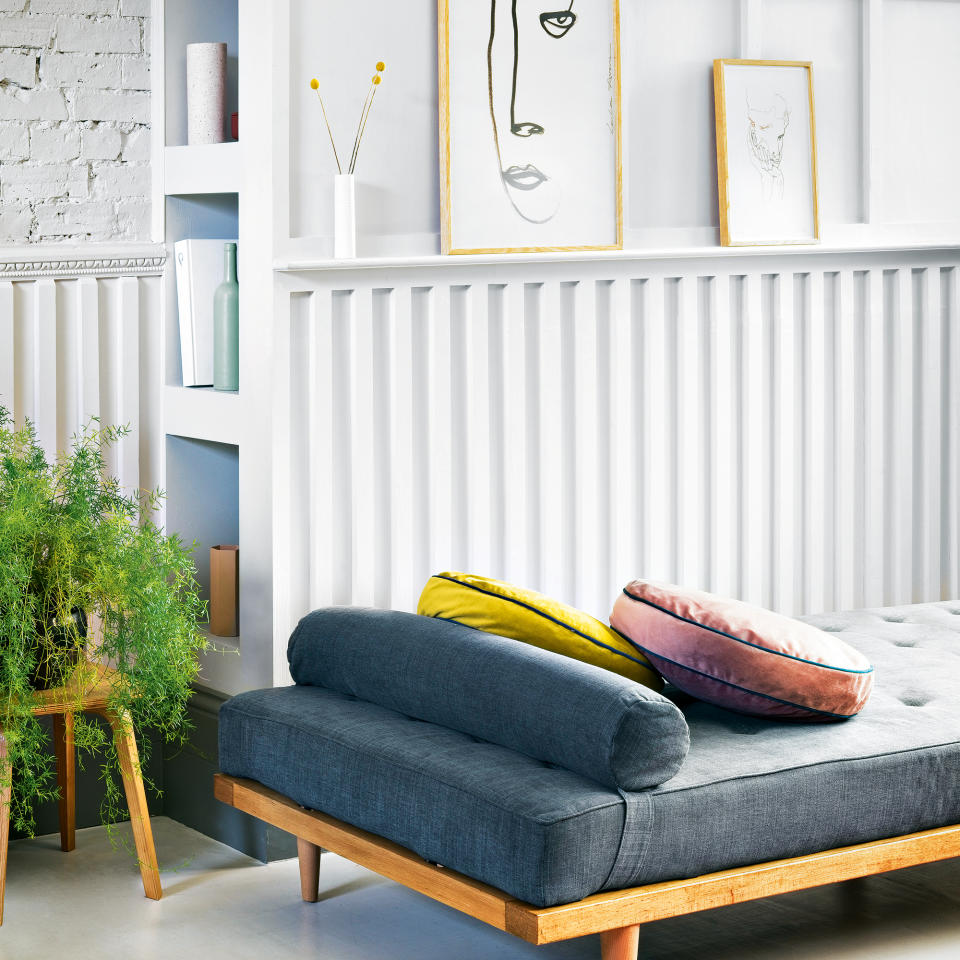 Grey painted panelled wall with hidden storage behind and a daybed in front