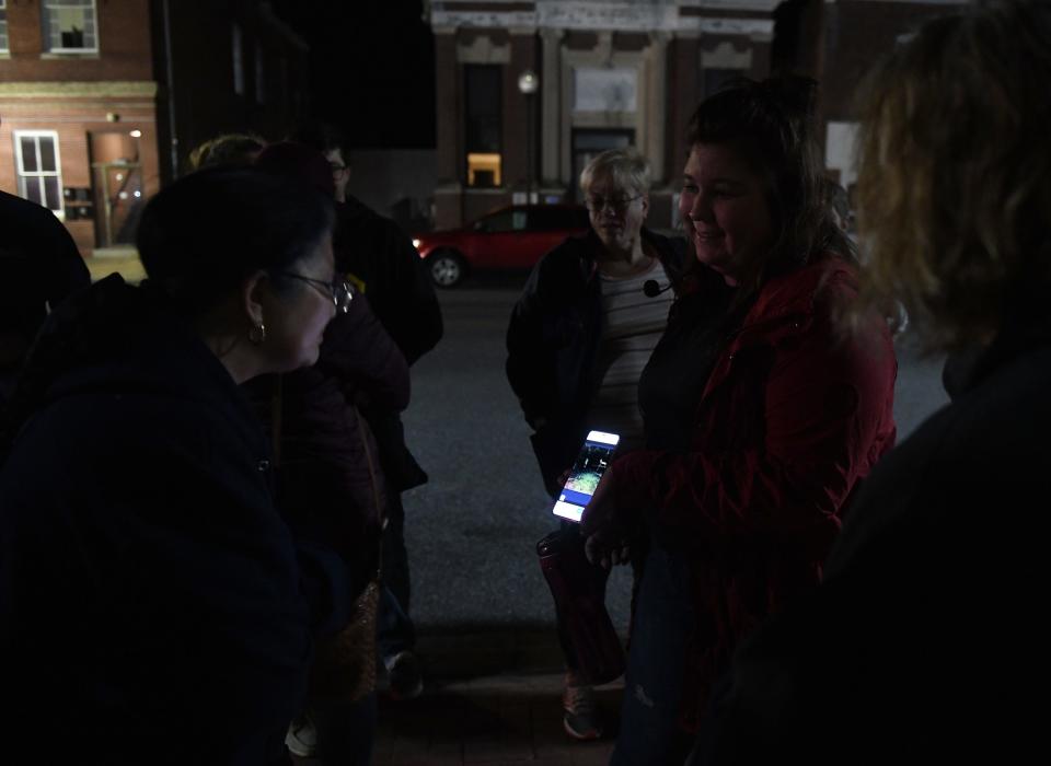 Chesapeake Ghost Tours guide Bre Bittner shows a photo of a haunting to the tour group Oct. 20, 2023, in Princess Anne, Maryland.