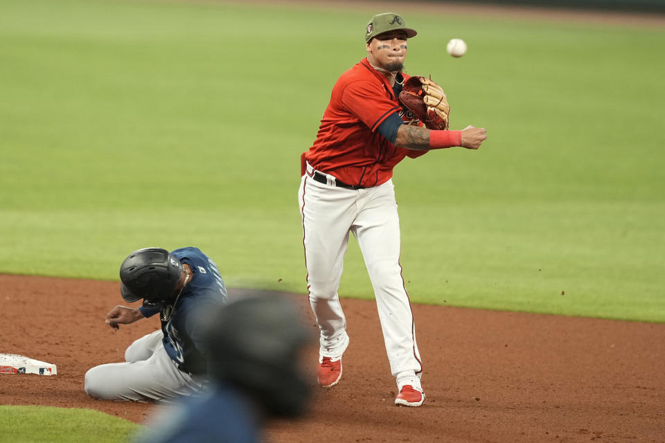 Atlanta Braves' Arcia, top, makes a double play at second base in the seventh inning of a baseball game against Seattle Mariners' Teoscar Hernandez, left, Friday, May 19, 2023, in Atlanta. (AP Photo/Brynn Anderson)