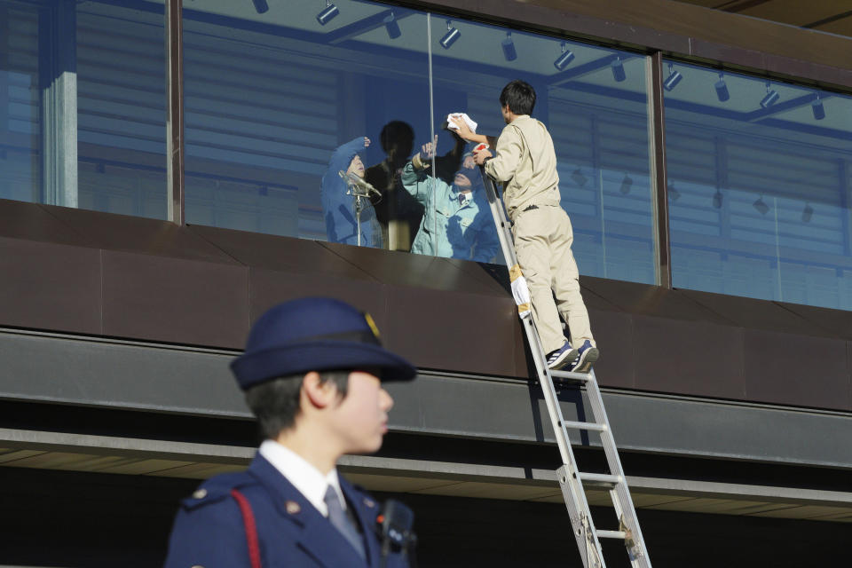 Workers clean the bullet-proofed balcony prior to Japan's Emperor Naruhito's public appearance with his imperial families at Imperial Palace in Tokyo Thursday, Jan. 2, 2020. (AP Photo/Eugene Hoshiko)
