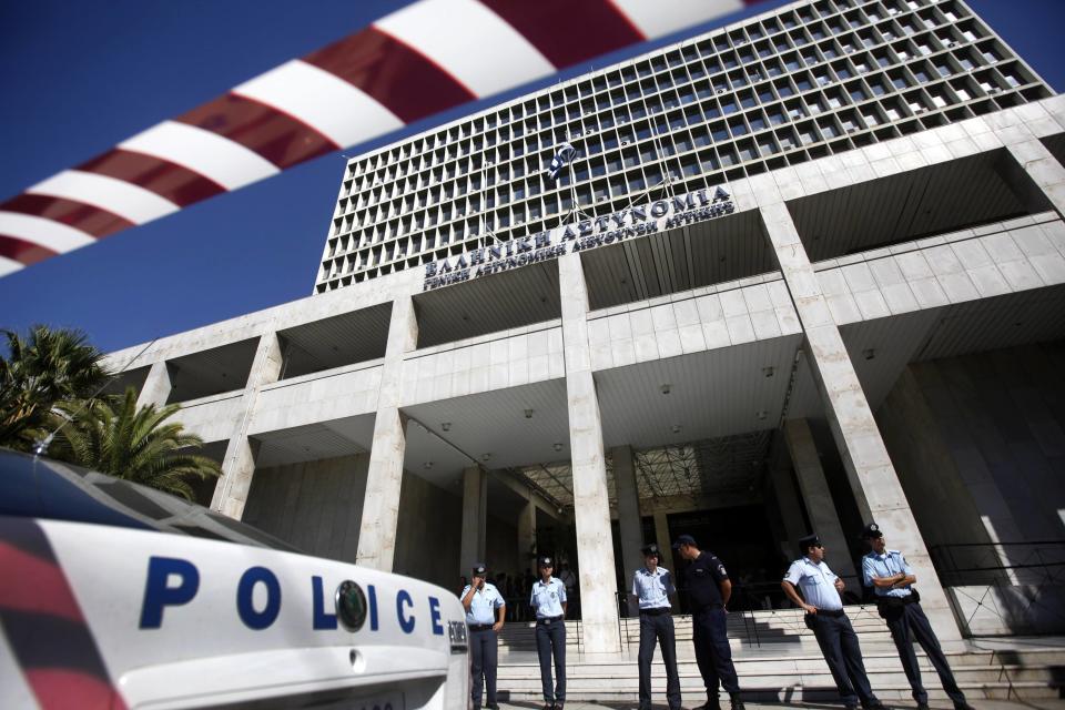 Police officers stand guard outside the Greek police headquarters in Athens