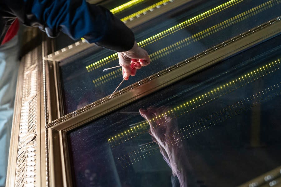 Amy Lubick, a supervisory conservator at the National Archives, runs a cotton swab over a display case that held the U.S. Constitution at National Archives in Washington on Thursday, Feb. 15, 2024. The National Archives building and galleries were evacuated on Feb. 14 after two protesters dumped powder on the protective casing around the U.S. Constitution. (AP Photo/Amanda Andrade-Rhoades)