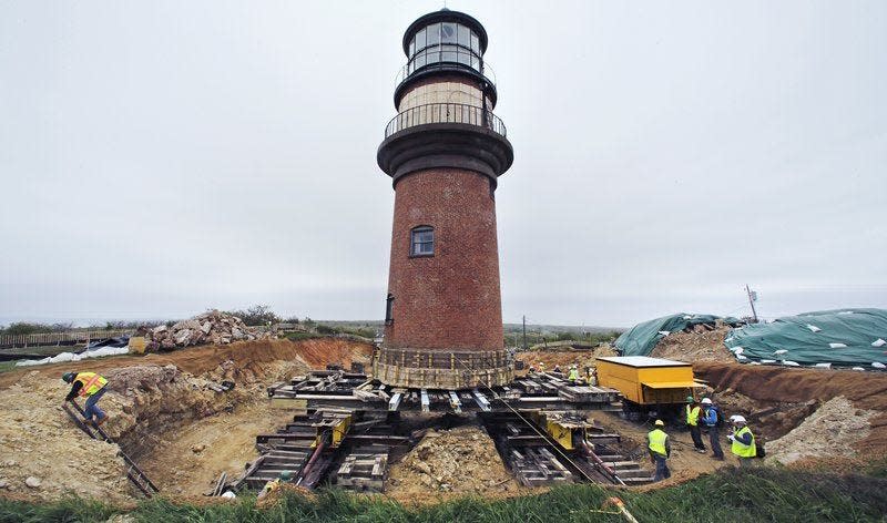 A worker climbs out of a hole dug around the Gay Head Lighthouse while moving the historic structure in Aquinnah, Mass., on the island of Martha’s Vineyard. The 160-year-old lighthouse took a multi-day trek to a new home slightly farther inland. The $3 million effort to move and save the structure was due to fear that it could tumble down a rapidly eroding cliffside.