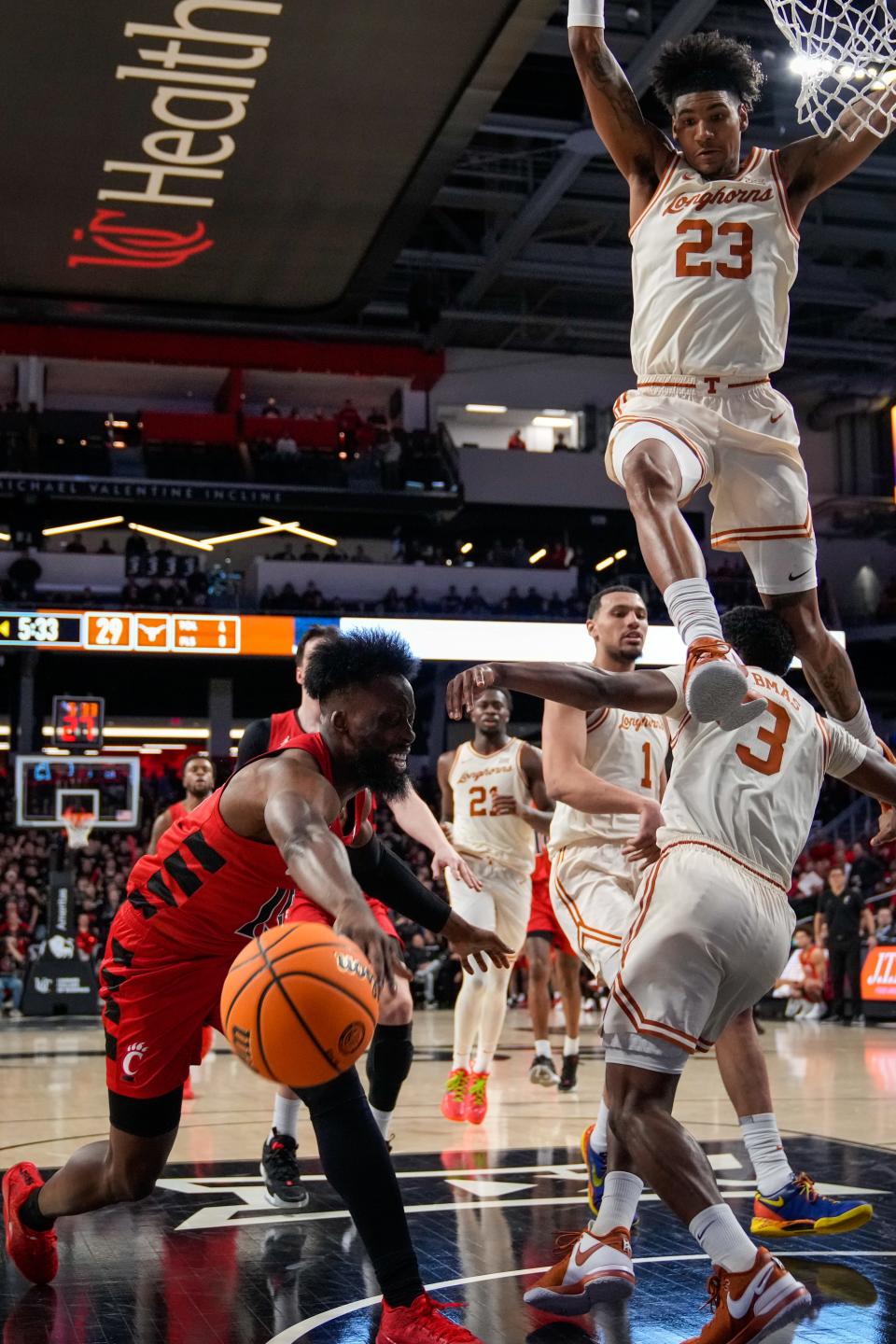 Texas Longhorns forward Dillon Mitchell (23) leaps over guard Max Abmas (3) as players collide over a loose ball Jan. 9 at Fifth Third Arena. Mitchell and the Longhorns beat the Bearcats 74-73.