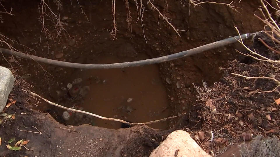 A hole in the ground partially filled with water (NBC New York)