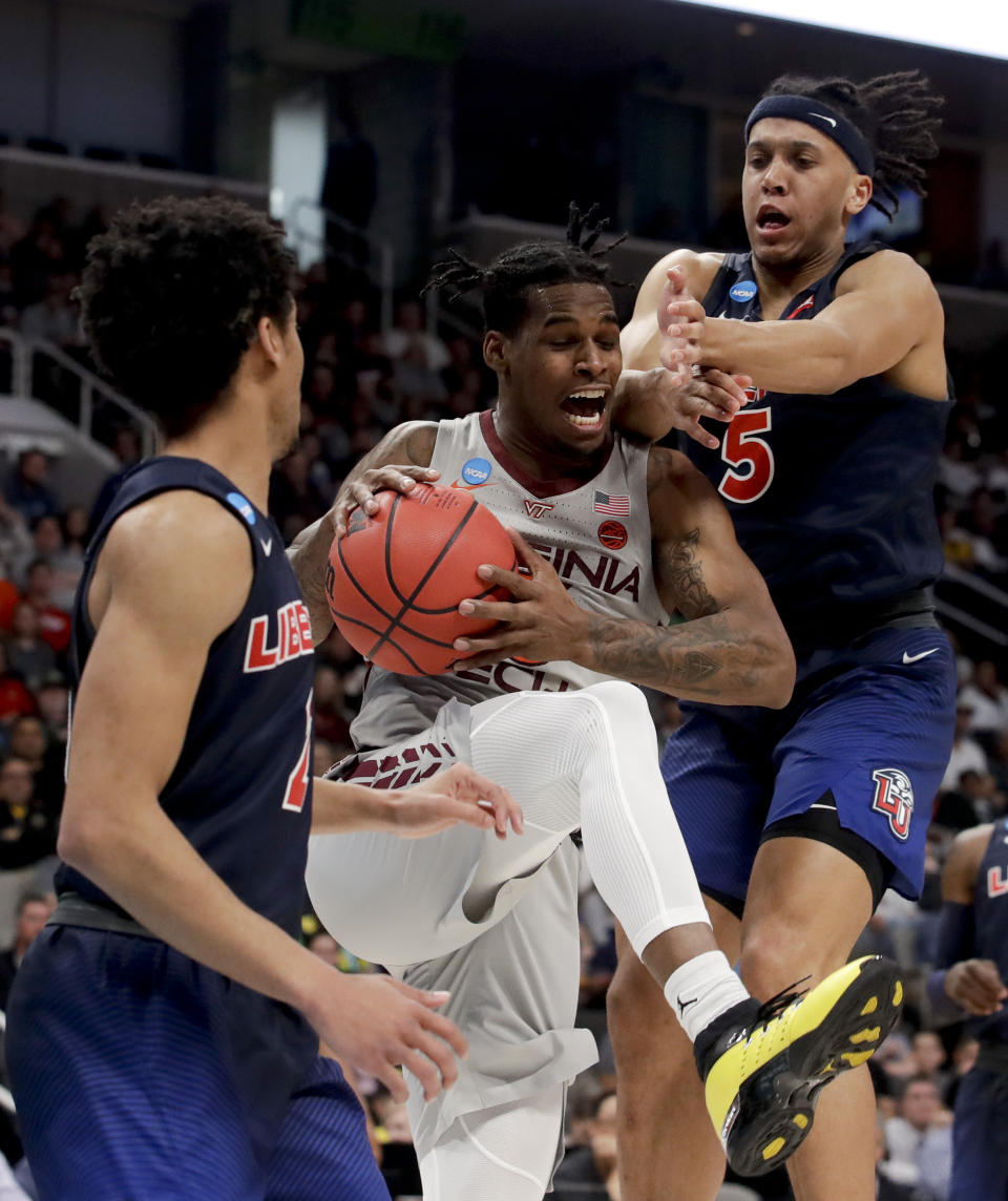 Virginia Tech guard Ahmed Hill, middle, drives to the basket between Liberty guard Darius McGhee, left, and forward Keenan Gumbs during the second half of a second-round game in the NCAA men's college basketball tournament Sunday, March 24, 2019, in San Jose, Calif. (AP Photo/Jeff Chiu)