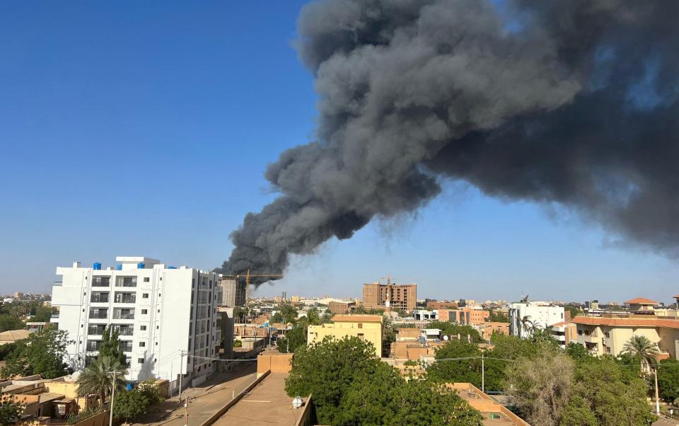 Smoke rises behind buildings near the airport in Khartoum on Wednesday - AFP