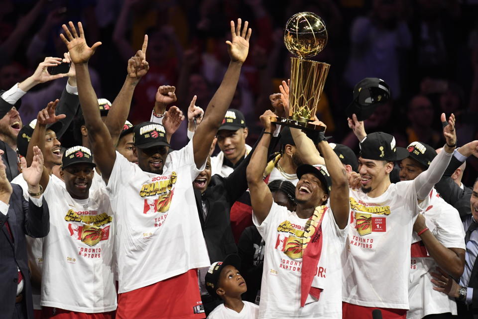 El base Kyle Lowry alza el trofeo de la NBA y los Raptors de Toronto festejan su triunfo sobre los Warriors de Golden State en el 6to juego de las finales de la NBA que les dio el título. (Frank Gunn/The Canadian Press via AP)