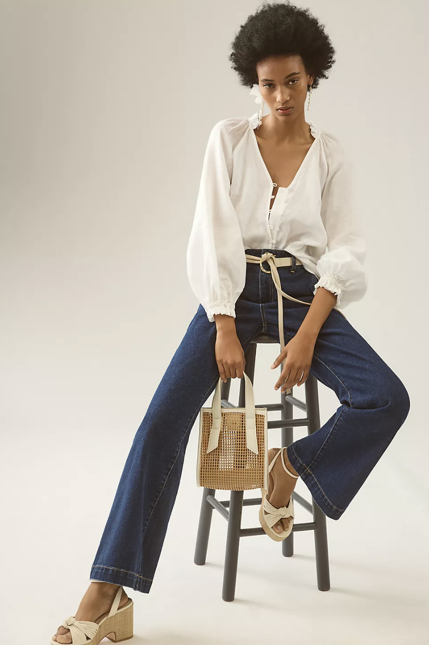 model with afro wearing white blouse and blue jeans, The Audie Linen Puff-Sleeve Blouse (Photo via Anthropologie)