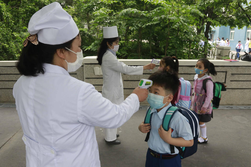 FILE - In this June 3, 2020, file photo, Kim Song Ju Primary school students have their temperatures checked before entering the school in Pyongyang, North Korea. Kim Yo Jong, the influential sister of North Korean leader Kim Jong Un, lambasted South Korean Foreign Minister Kang Kyung-wha for questioning the North’s claim to be coronavirus free, warning Wednesday, Dec. 9, 2020 of potential consequences for the comments. (AP Photo/Jon Chol Jin, File)