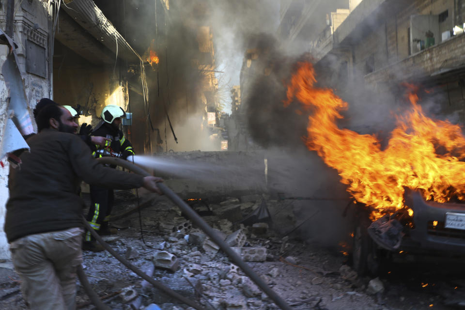 This photo provided by the Syrian Civil Defense White Helmets, which has been authenticated based on its contents and other AP reporting, shows Syrian White Helmet civil defense workers extinguishing flames from a burning car, in the town of Afrin, north of Aleppo, Thursday, Jan. 20, 2022. The rocket attack on Afrin, controlled by Turkey-backed opposition fighters, killed several civilians and wounded over a dozen people on Thursday, Syrian rescuers and a war monitor said. Both blamed U.S-backed Syrian Kurdish forces for the attack. (Syrian Civil Defense White Helmets via AP)